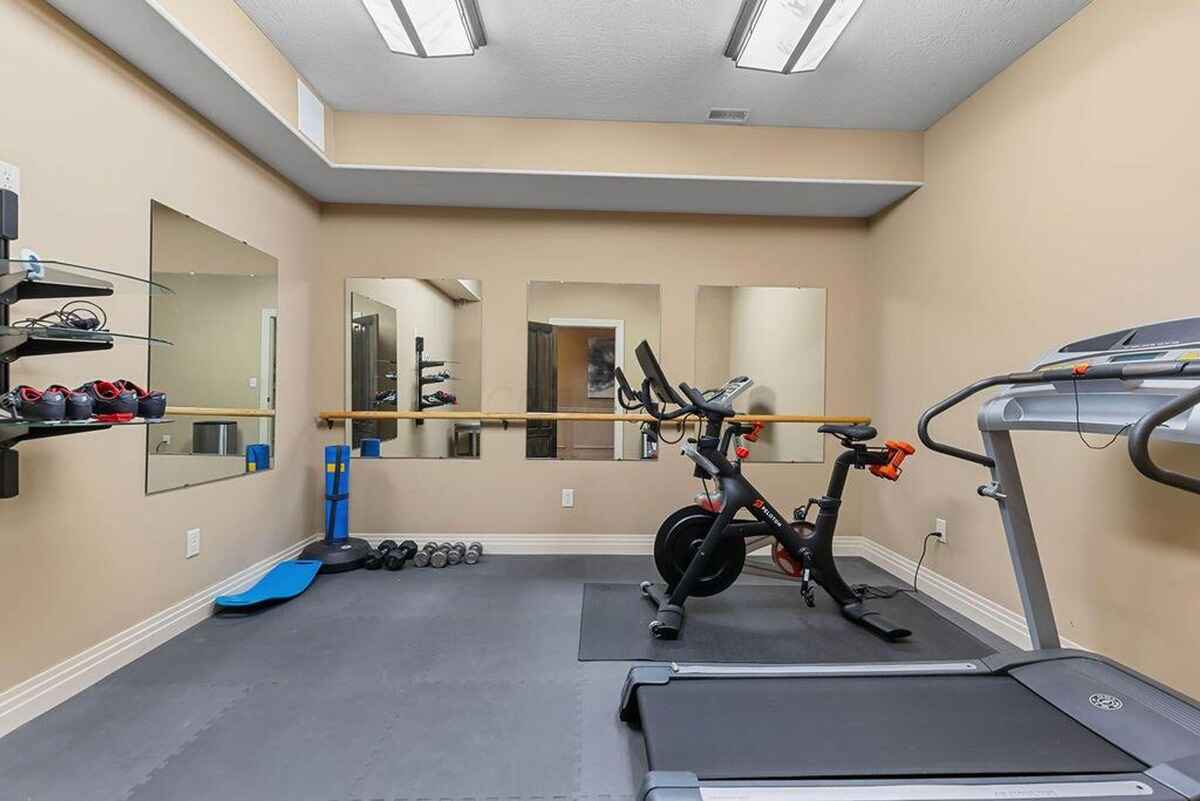 Fitness room offers exercise equipment, mirrored walls, and rubber flooring for workouts.