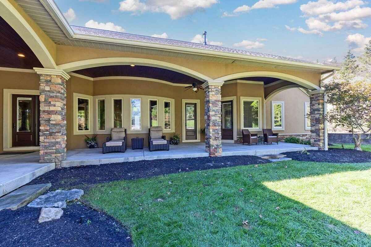 Expansive patio showcasing stone accents, multiple seating arrangements, and a connection to green lawns and scenic surroundings.