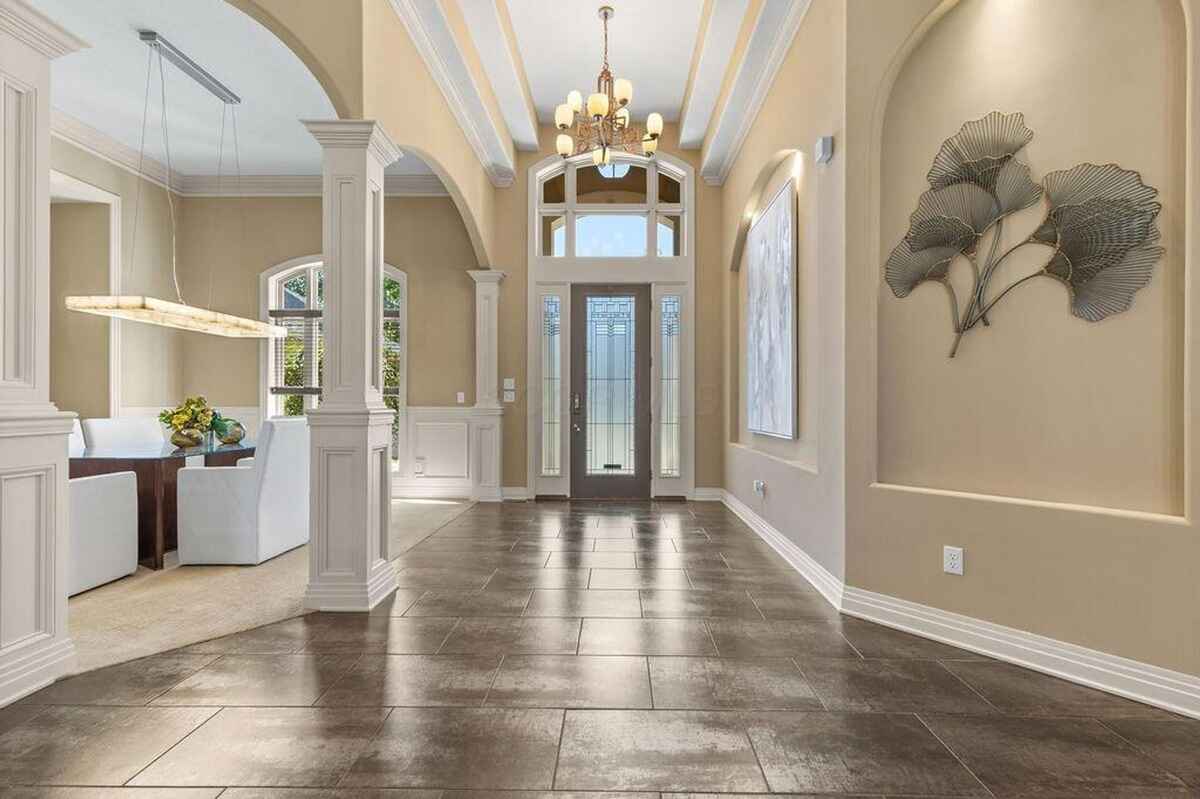 Dining area is framed by archways and includes a modern light fixture above a rectangular dining table.