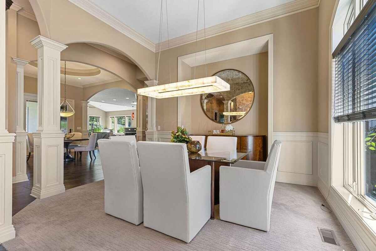 Dining area is framed by archways and includes a modern light fixture above a rectangular dining table.