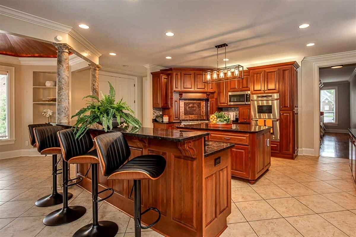 Kitchen island with bar seating, detailed woodwork, and decorative columns near the entrance.