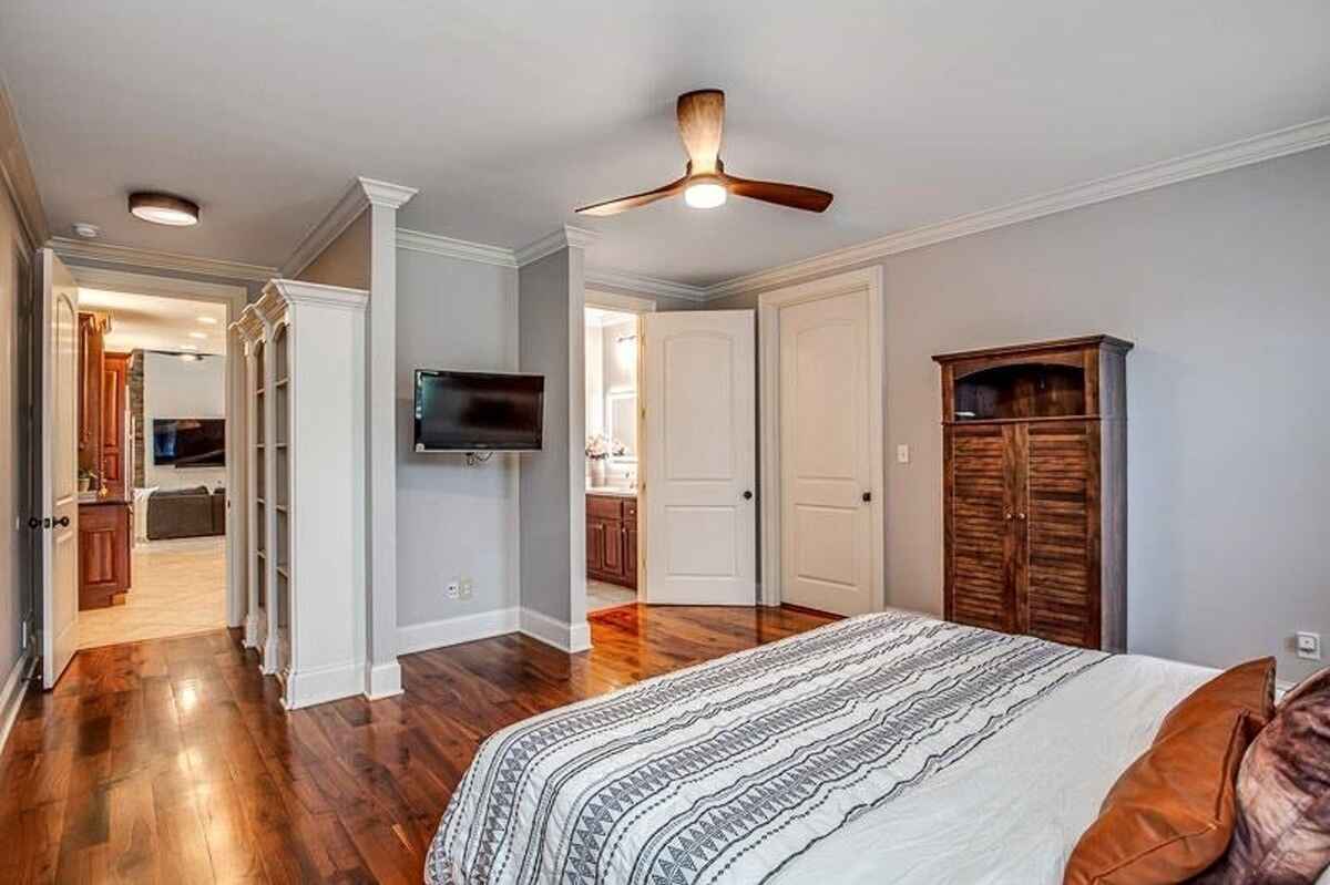 Secondary bedroom with ceiling fan, built-in shelving, and access to an en-suite bathroom.