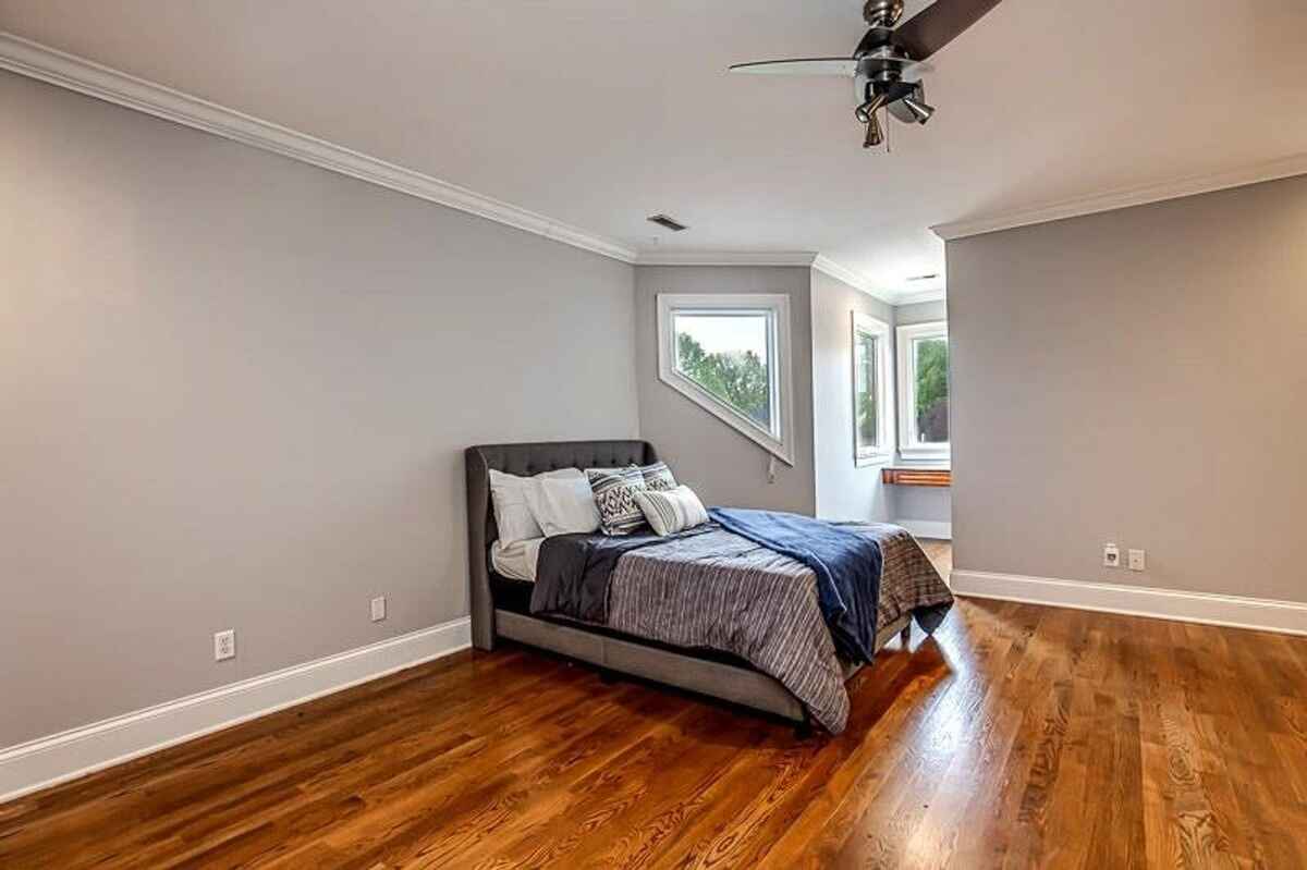 Bedroom featuring neutral gray walls, angled windows, and a modern ceiling fan.