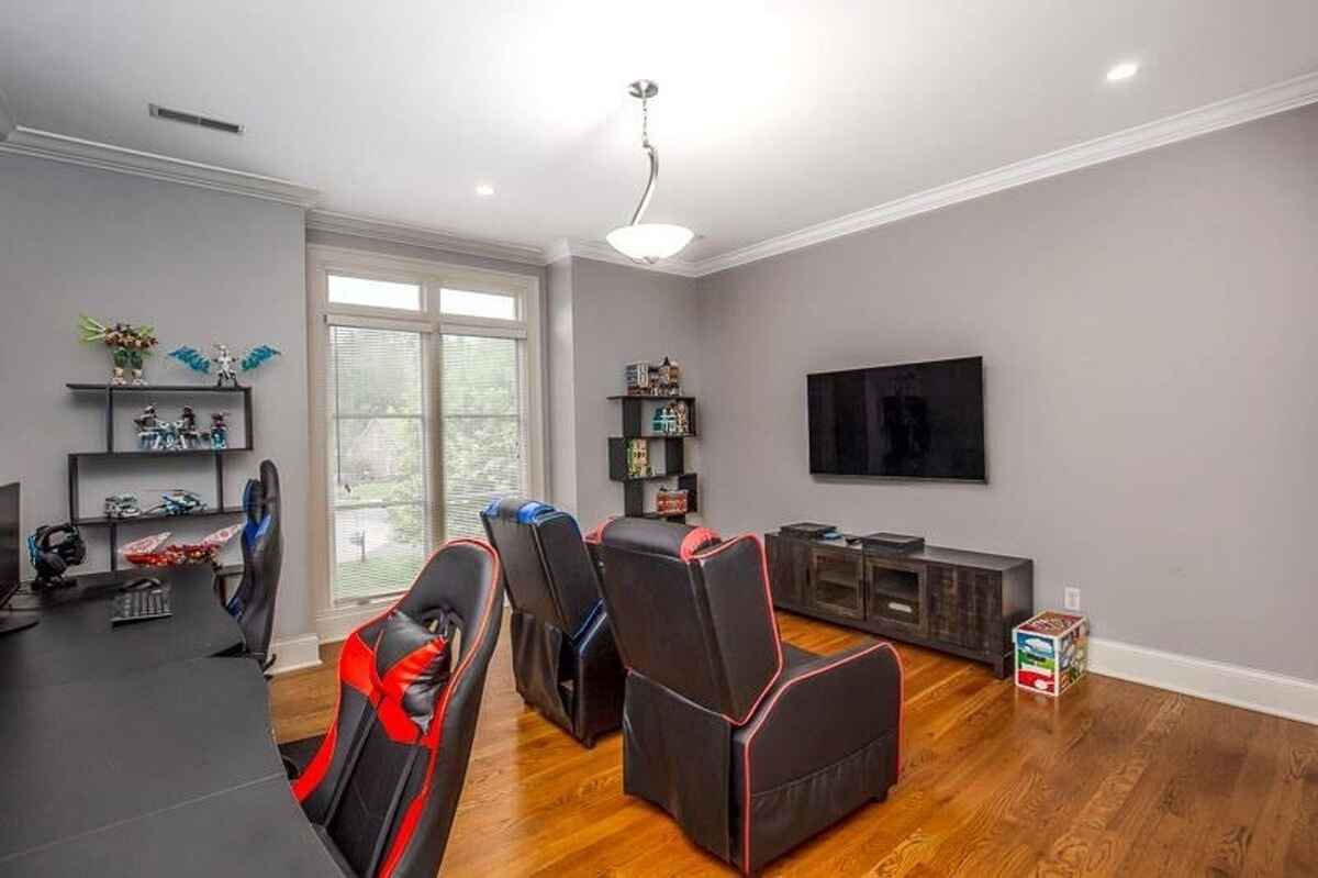 Entertainment room with gaming chairs, a mounted television, and shelves for decorations.