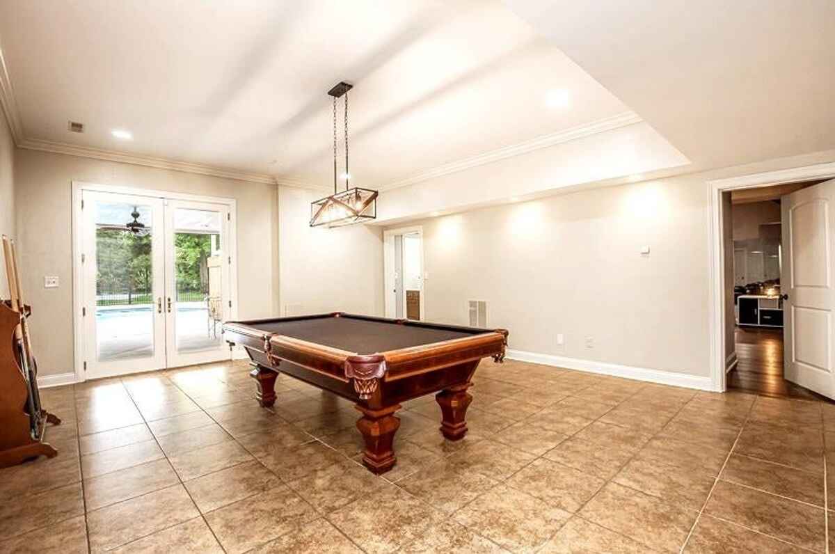 Recreation room with a pool table, tiled flooring, and access to an outdoor area through glass doors.