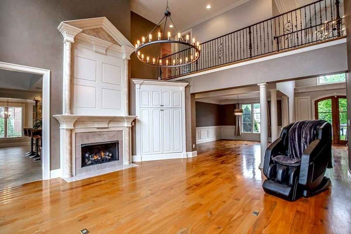 Living room with hardwood floors, a fireplace, a chandelier, and visible upper railing of the second floor.