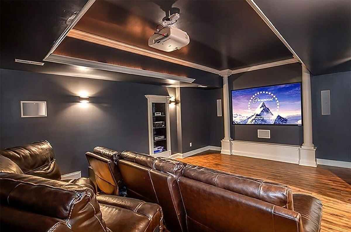 Home theater room featuring a projector, large screen, and leather reclining seats.