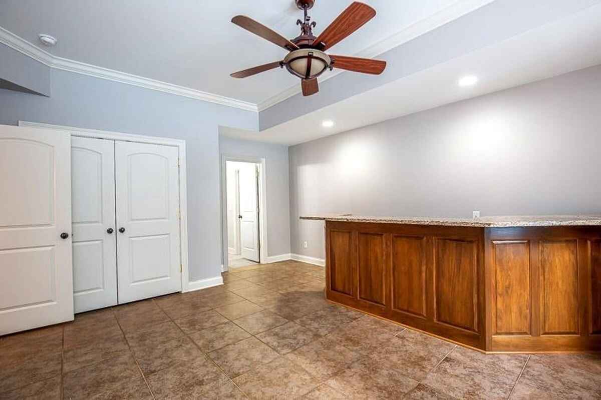 Room with a tiled floor, built-in bar, and ceiling fan.