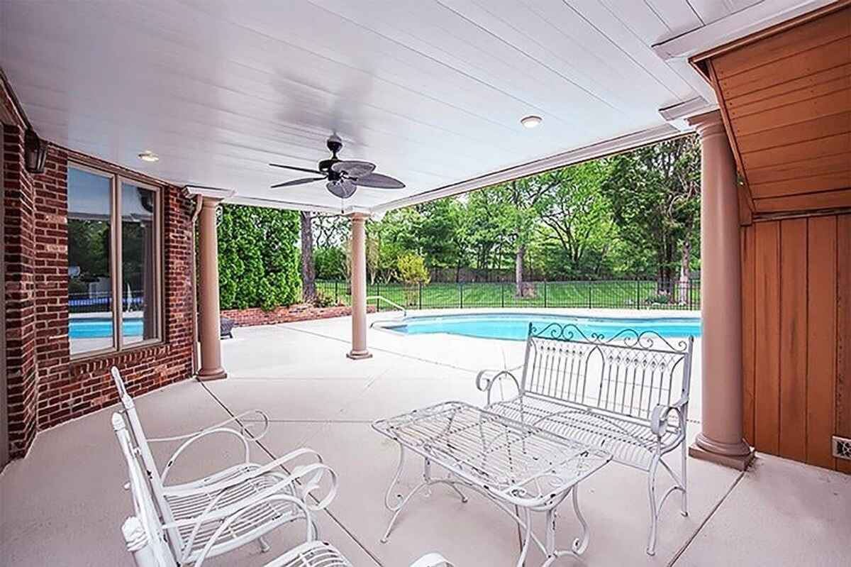 Covered patio with ceiling fan, outdoor seating, and view of the pool.