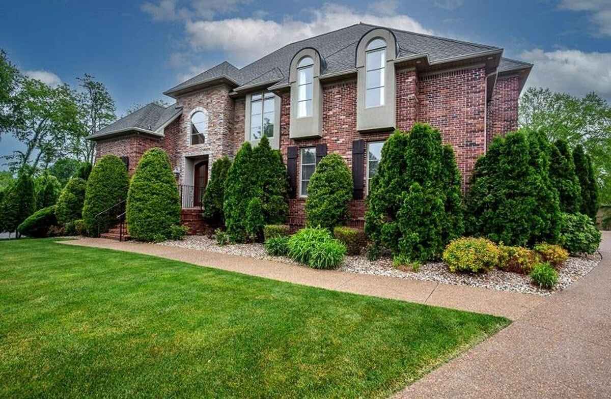 Brick exterior with landscaping, walkway, and neatly trimmed shrubs.