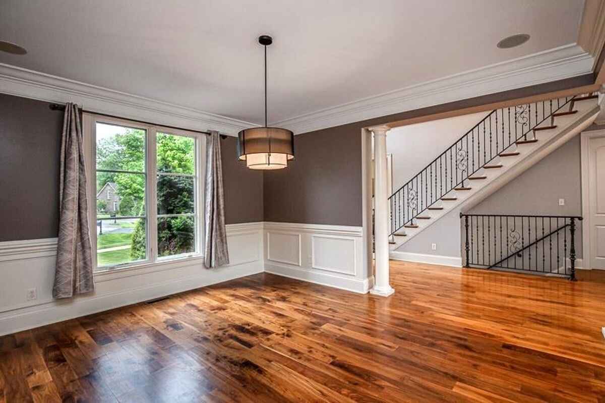 Dining area with hardwood floors, large windows, and adjacent staircase with decorative railings.