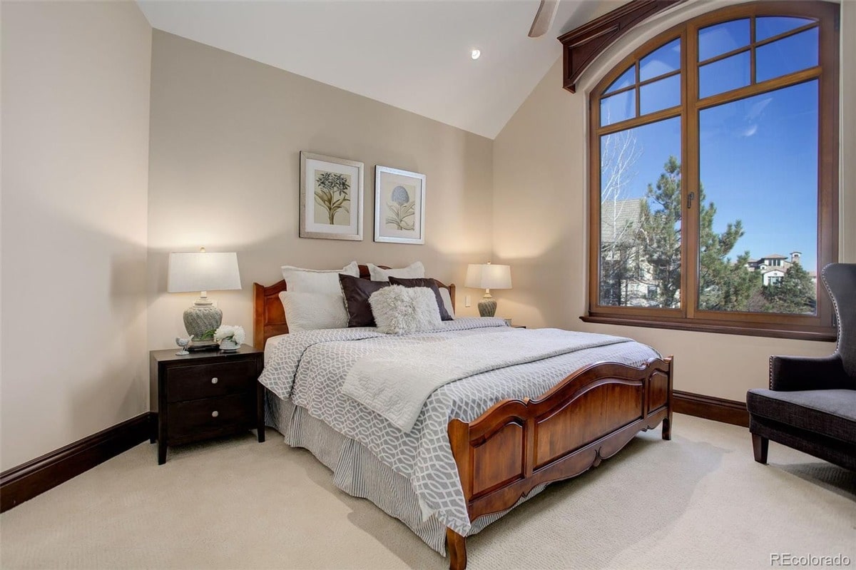 Elegant design details such as a rich wood bed frame and neutral color scheme create a sophisticated ambiance in this bedroom. The room's thoughtful layout and comfortable furnishings provide a luxurious and relaxing space.