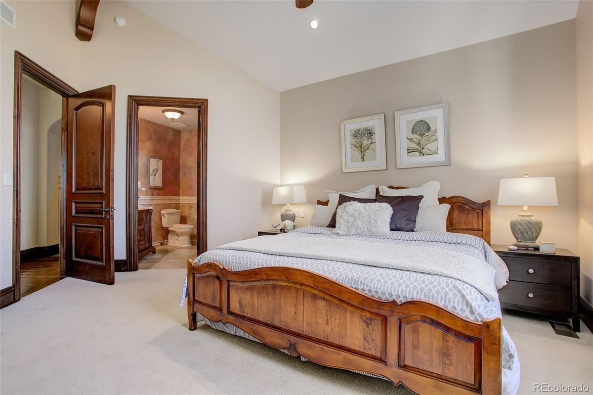 Elegant details such as a rich wood bed frame and sophisticated artwork create a refined atmosphere in this master bedroom. The room's thoughtful layout and calming color scheme provide a luxurious and relaxing space.