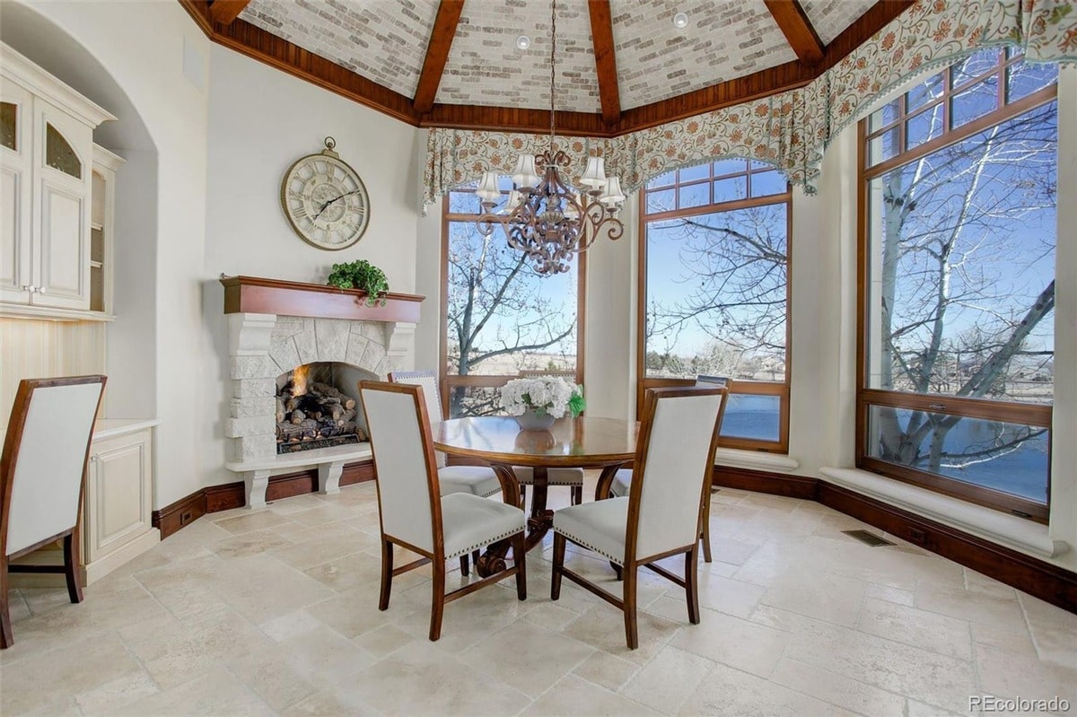 This charming breakfast nook offers a cozy and inviting space for morning meals, featuring a fireplace and large windows offering scenic views. The room's warm color palette and comfortable seating create a relaxed and intimate atmosphere.