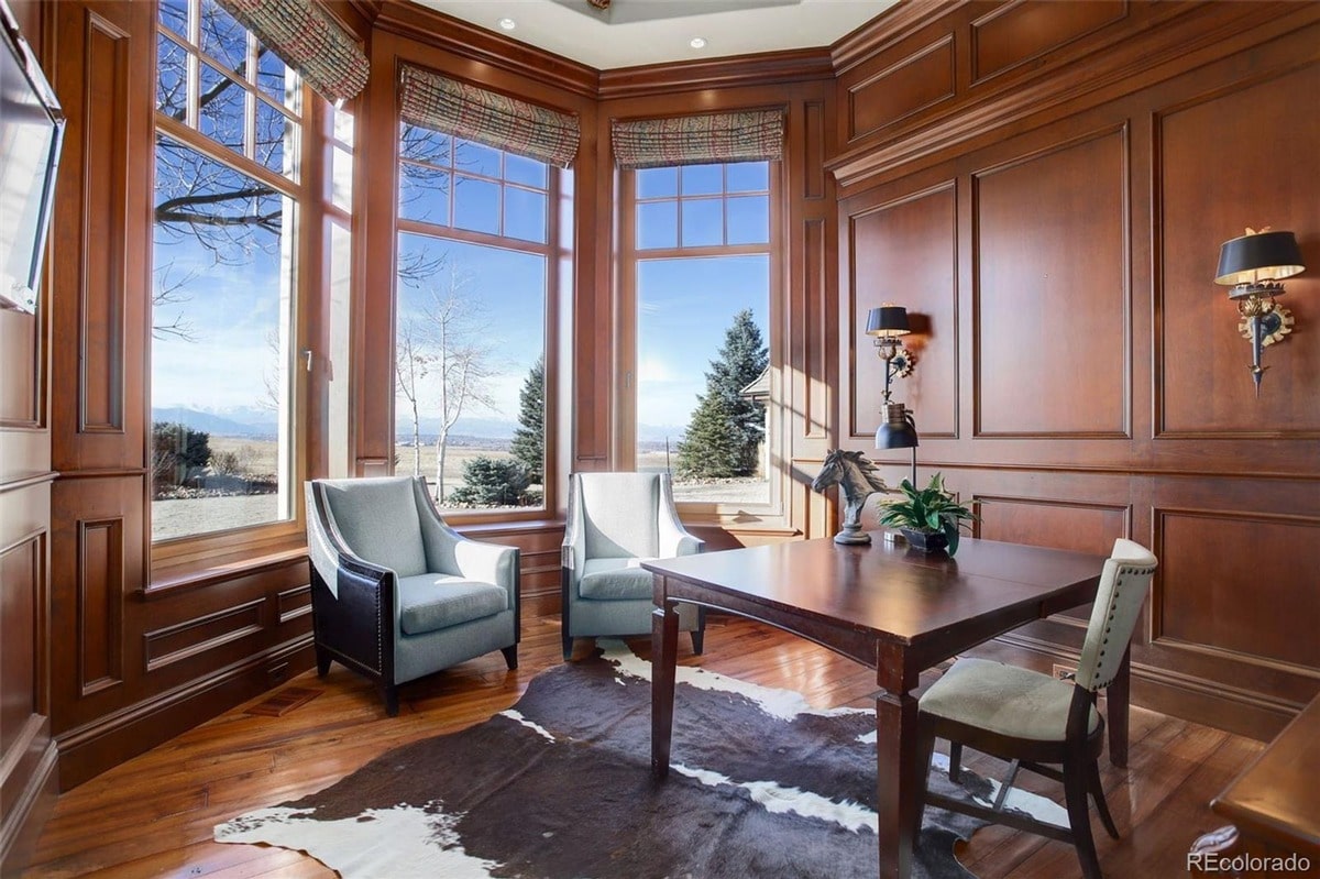 Classic design elements such as rich wood paneling and a spacious layout define this sophisticated home office. The room's thoughtful design and comfortable furnishings create a productive and inviting workspace.