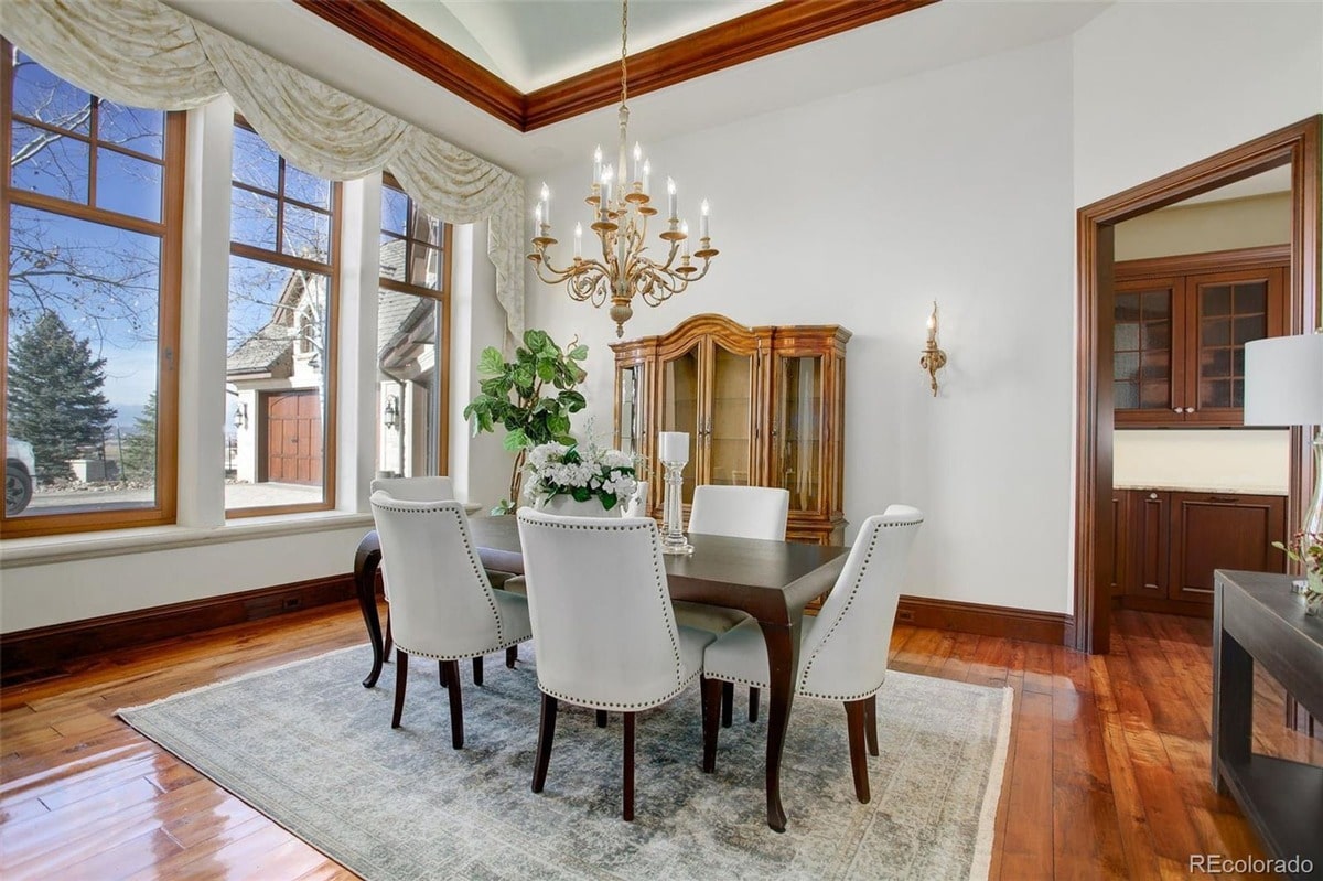 Bathed in natural light from a wall of windows, this dining room offers breathtaking views of the surrounding landscape. The room's elegant furnishings and warm color palette create a sophisticated and inviting atmosphere.