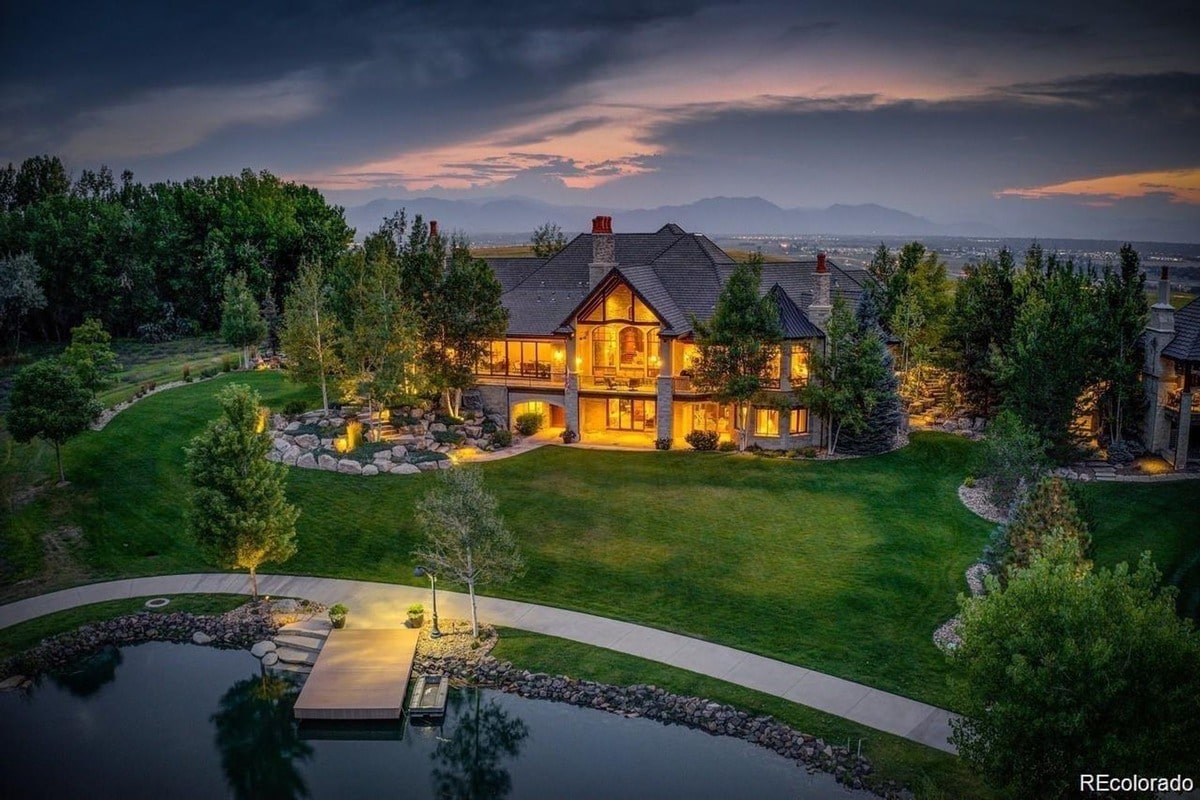 Nestled on a sprawling estate, this opulent residence boasts breathtaking mountain views and a serene private pond. The meticulously landscaped grounds and warm, inviting glow of the home at dusk create an atmosphere of unparalleled luxury and tranquility.