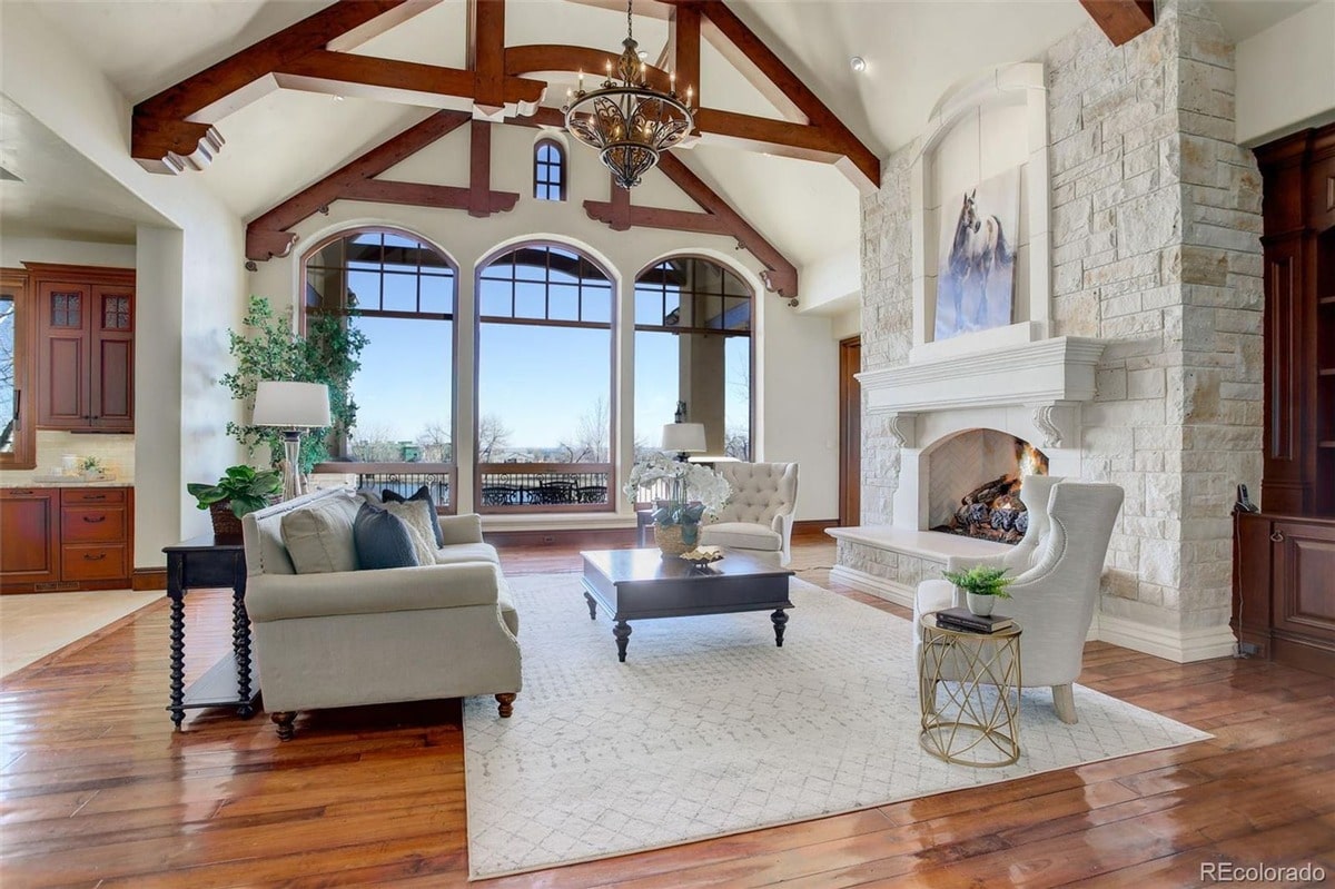 A warm and inviting atmosphere is created by the combination of natural materials, comfortable seating, and a crackling fireplace. The expansive windows and high ceilings enhance the sense of spaciousness and tranquility.