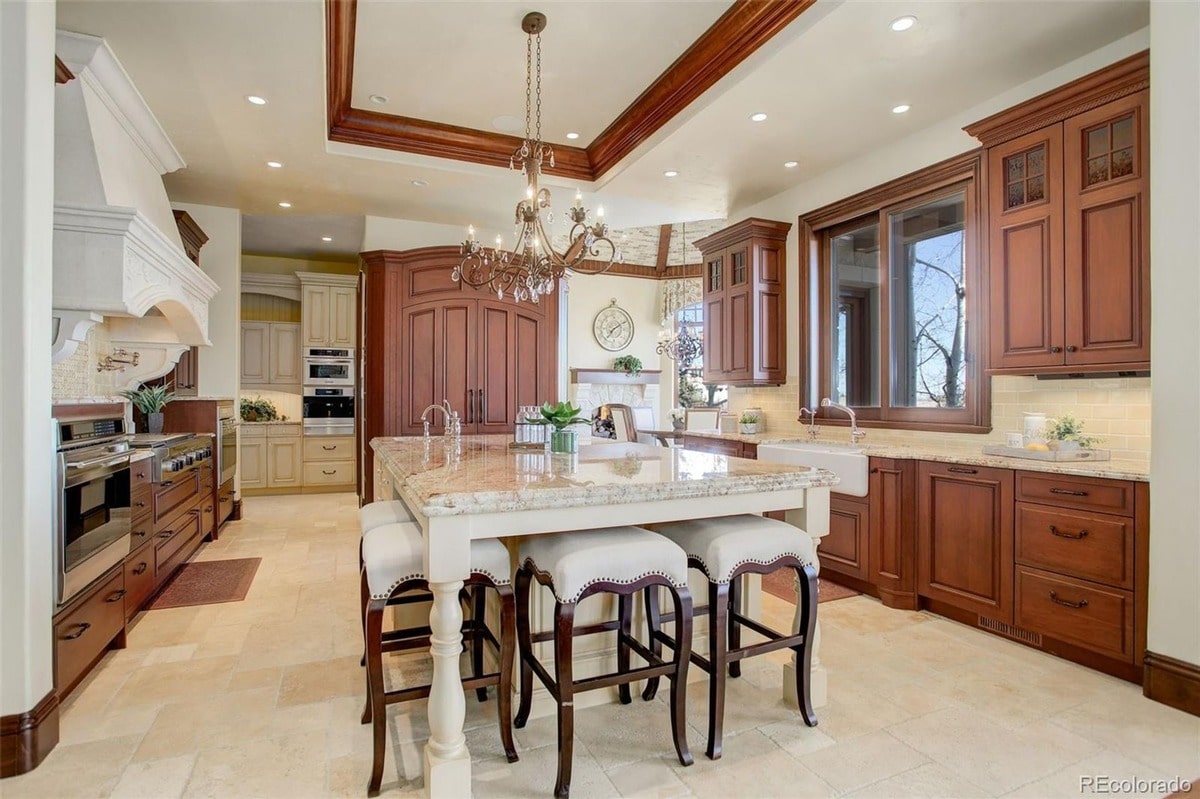 This elegant kitchen boasts a sophisticated design with rich wood cabinetry, a large center island, and high-end appliances. The combination of warm tones and natural light creates a welcoming and functional space.