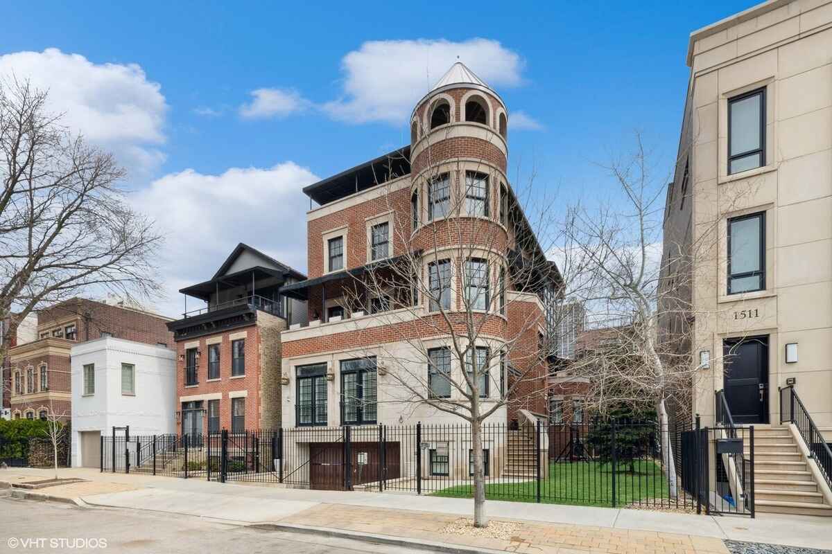 Multi-level brick building with a turret and fenced yard.