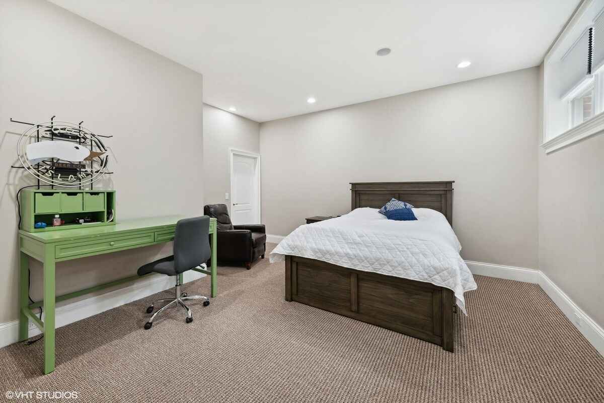 Bedroom includes a dark wooden bed frame, a green desk with a chair, and carpeted flooring.