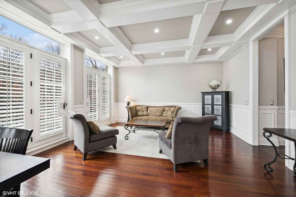 Living room featuring coffered ceiling, hardwood floors, and large windows.