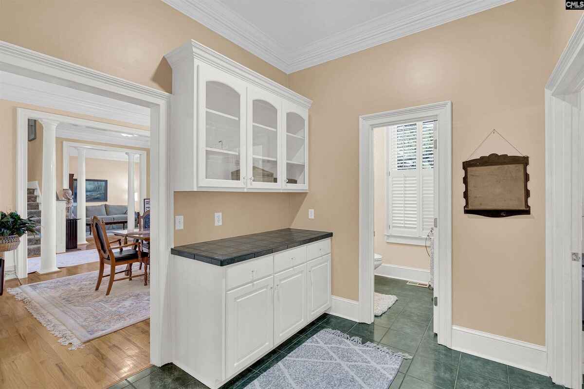 Butler's pantry area with white cabinetry and a tiled floor connecting to adjacent spaces.