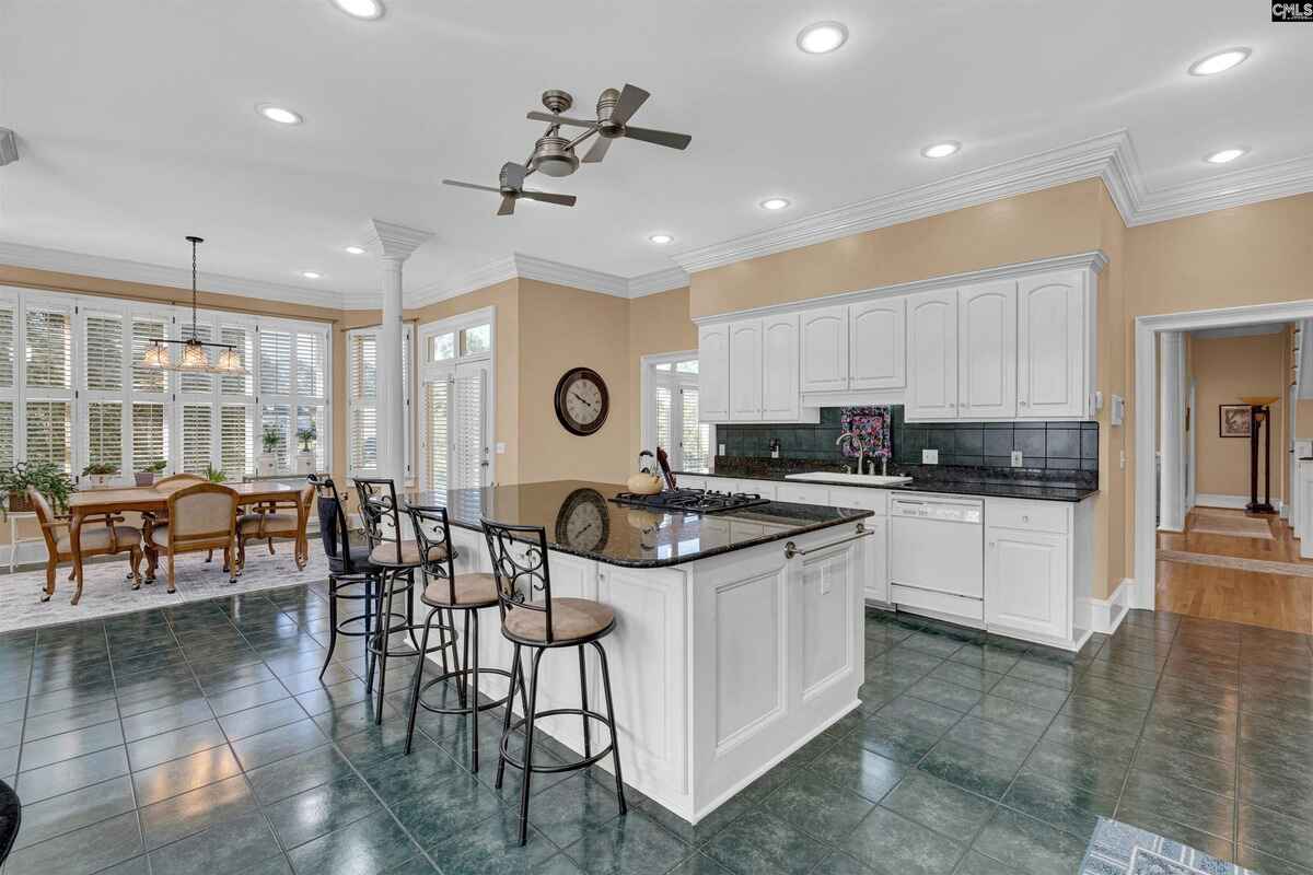 Kitchen features an island with bar seating, white cabinetry, and tile flooring.