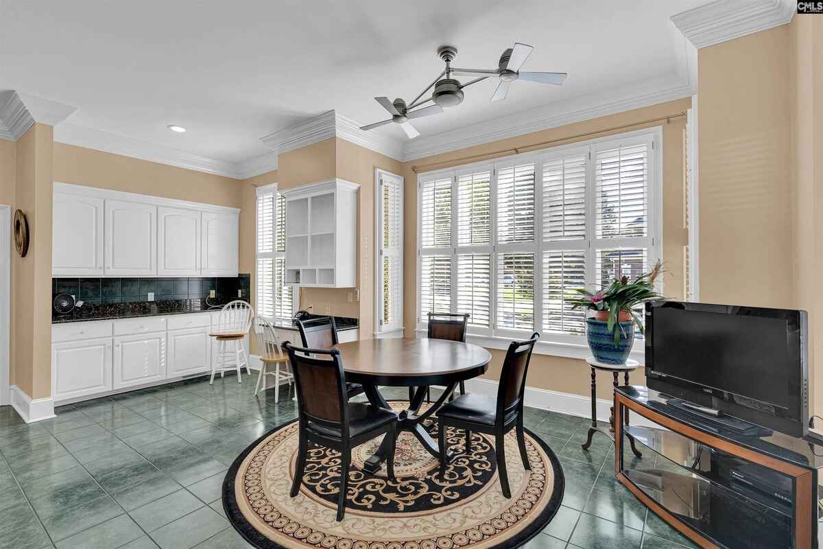 Breakfast area includes a round table, built-in cabinetry, and large windows with shutters.