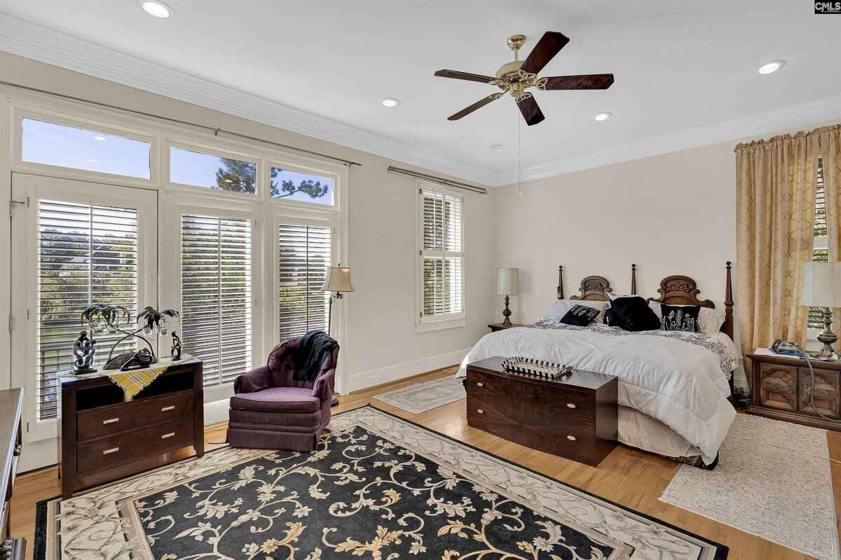 Master bedroom includes a seating area, large windows with shutters, and a ceiling fan.