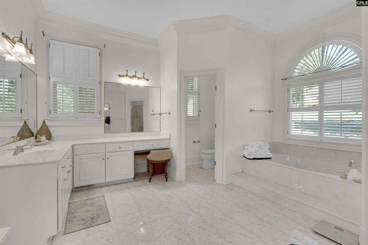 Luxurious bathroom with a soaking tub, large vanity area, and an arched window.