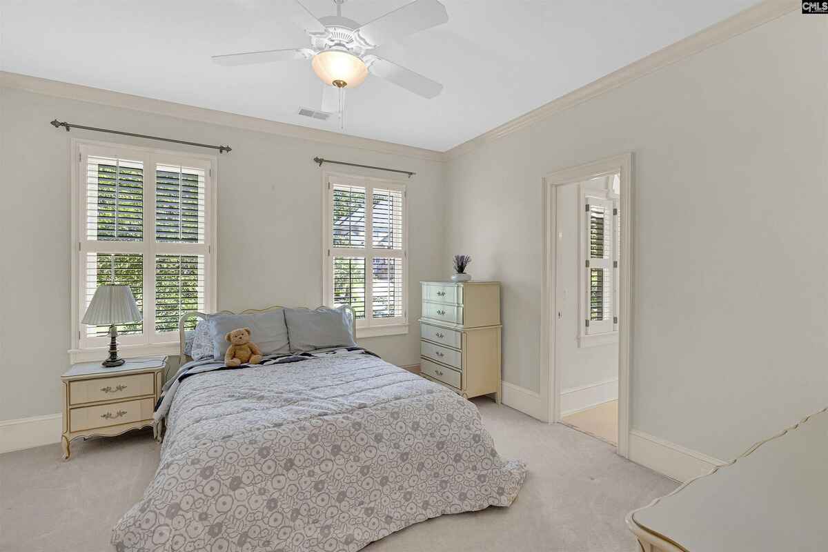 Bedroom with light decor, simple furnishings, and ample natural light from two windows.