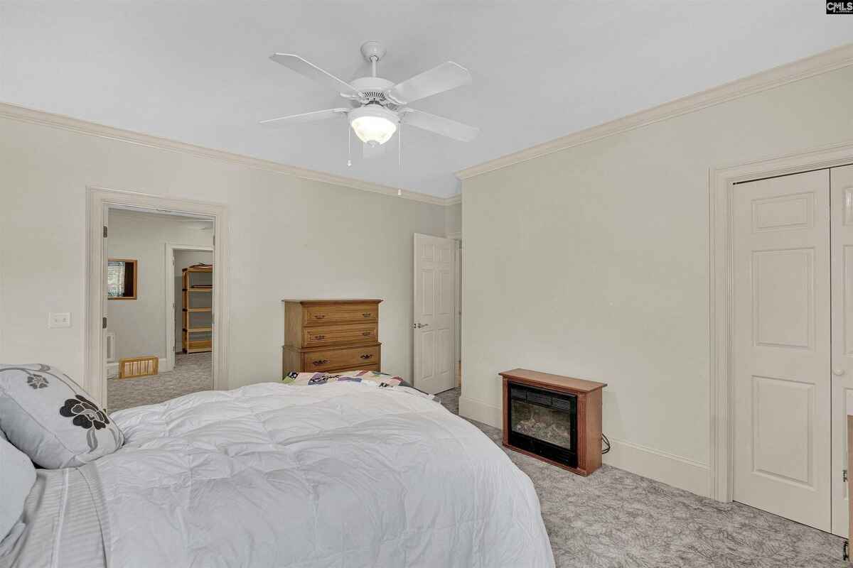 Primary bedroom with large windows, a ceiling fan, and a comfortable seating area.