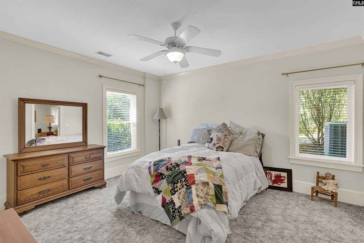 Bedroom showcases light-colored walls, a bed with quilt, and natural lighting from windows.