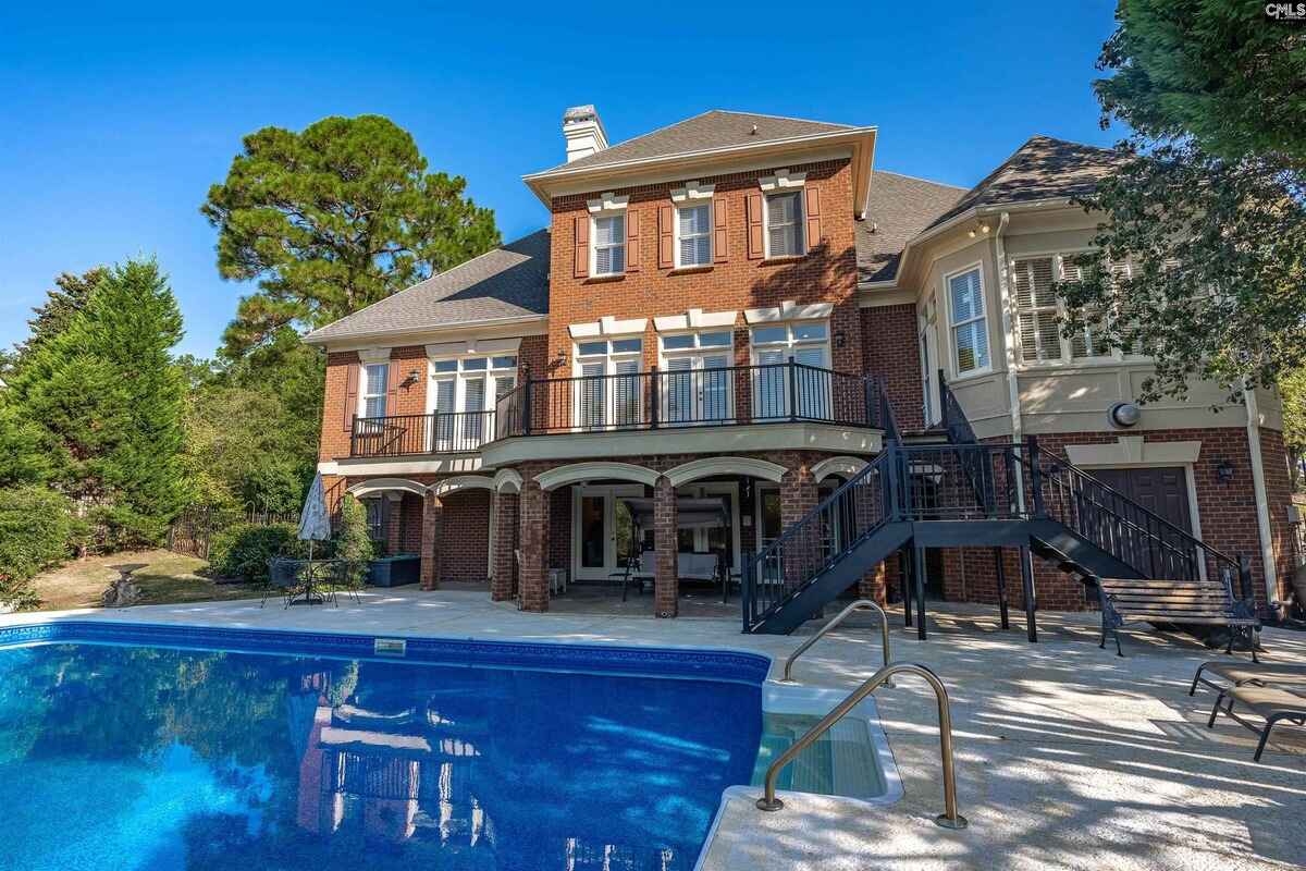 Brick house with a swimming pool, patio, and a multi-level deck with a staircase.