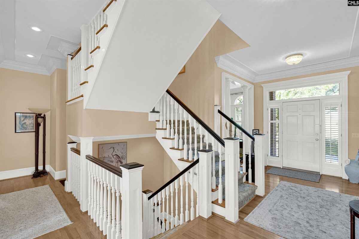 Interior staircase with white balusters and wooden handrails in a bright foyer.