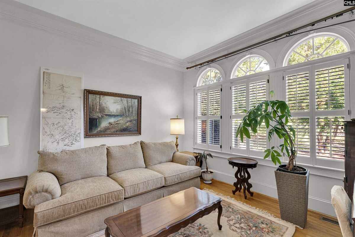 Living room with arched windows, a beige couch, and a plant in a corner.