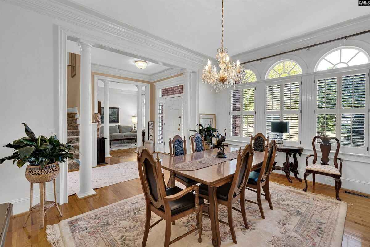 Dining room featuring a chandelier, wooden furniture, and large windows with white shutters.