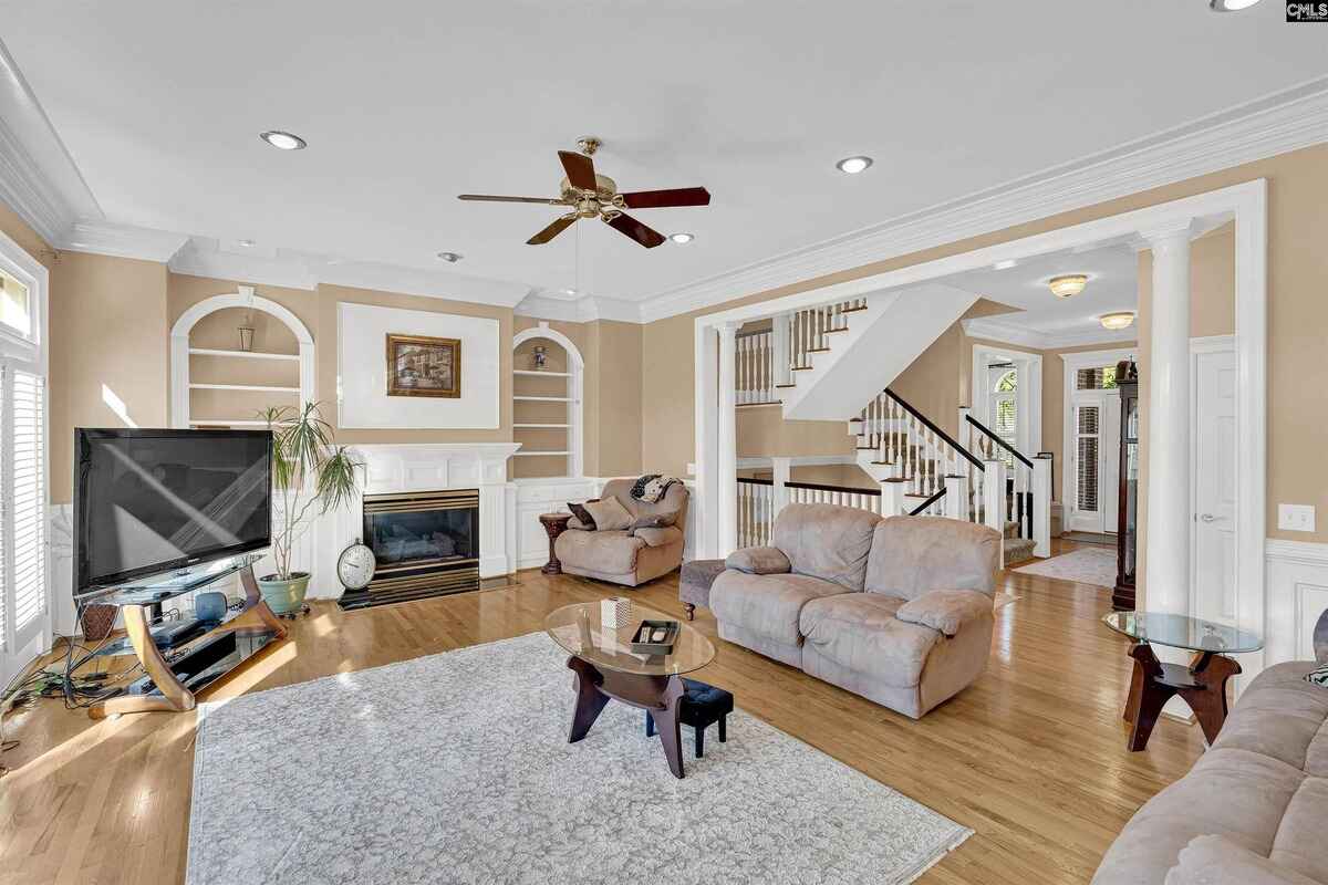 Family room with built-in shelves, a fireplace, and a staircase in the background.