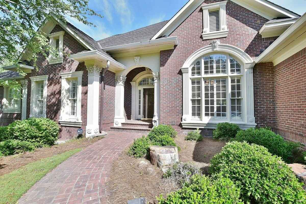 Brick exterior of the house features elegant columns and arched windows with detailed trim.