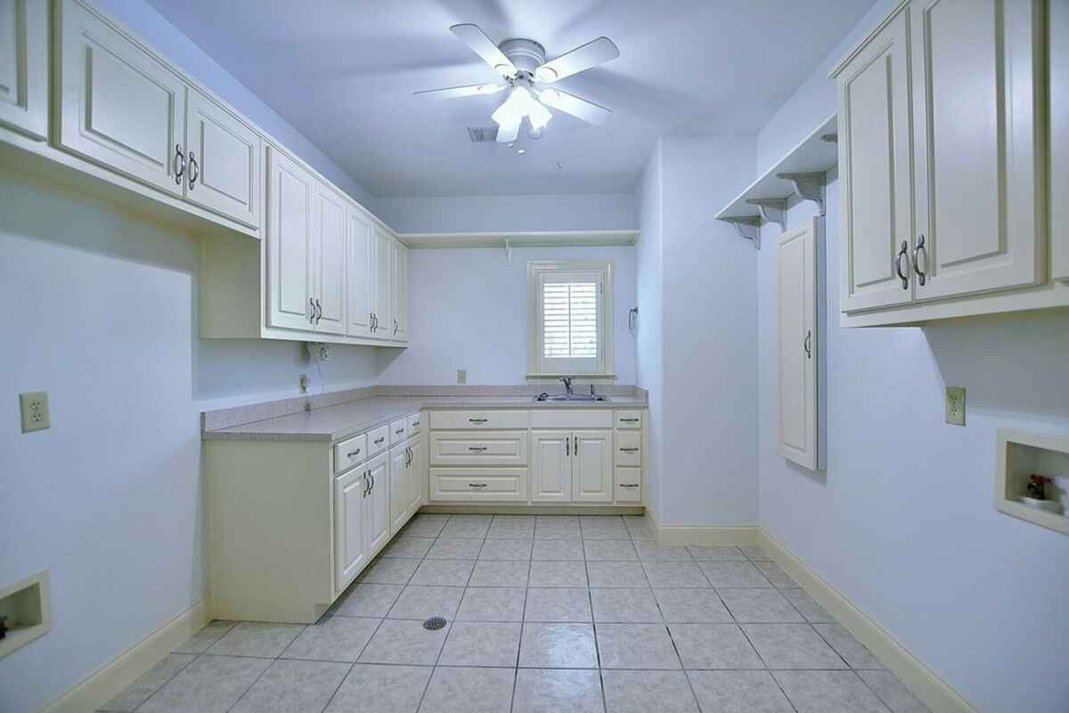 Laundry room features ample cabinetry, tiled flooring, and a small window for natural light.