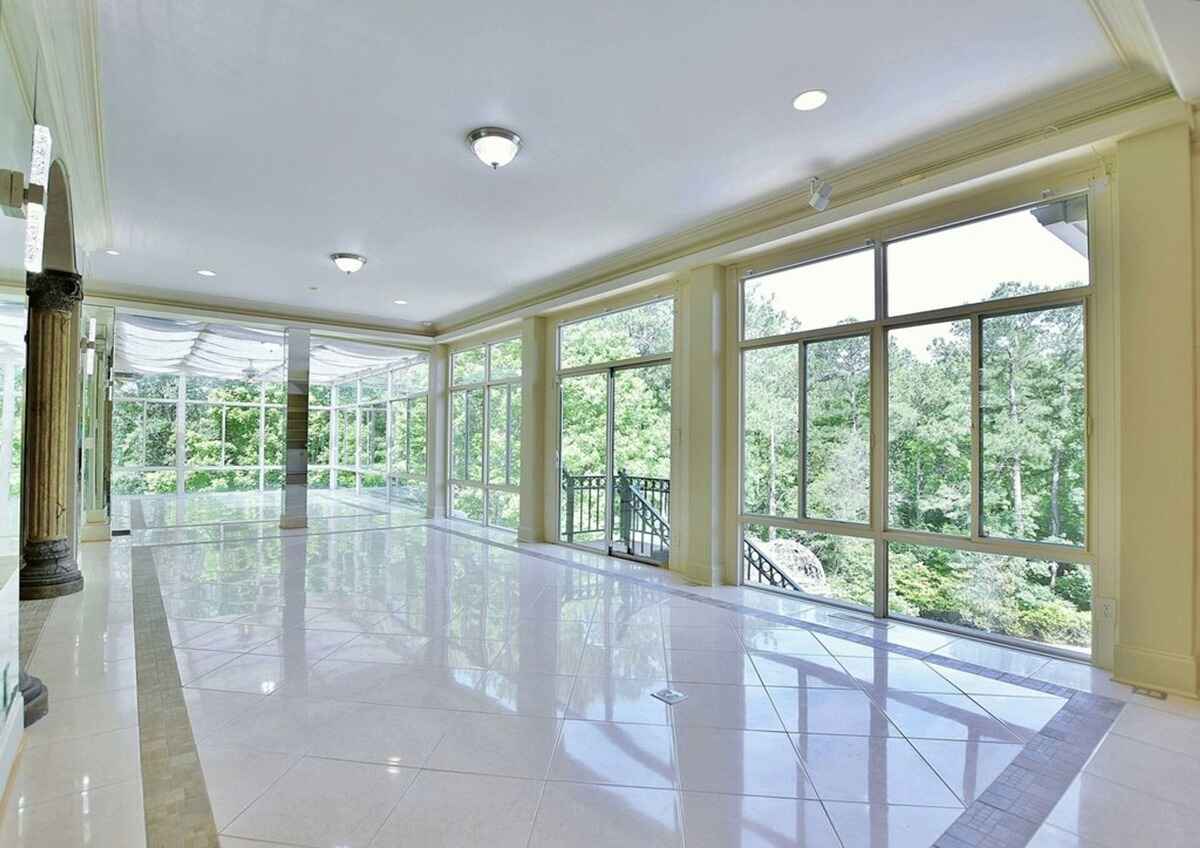 Sunroom showcases expansive windows, glossy tiled flooring, and views of the surrounding greenery.