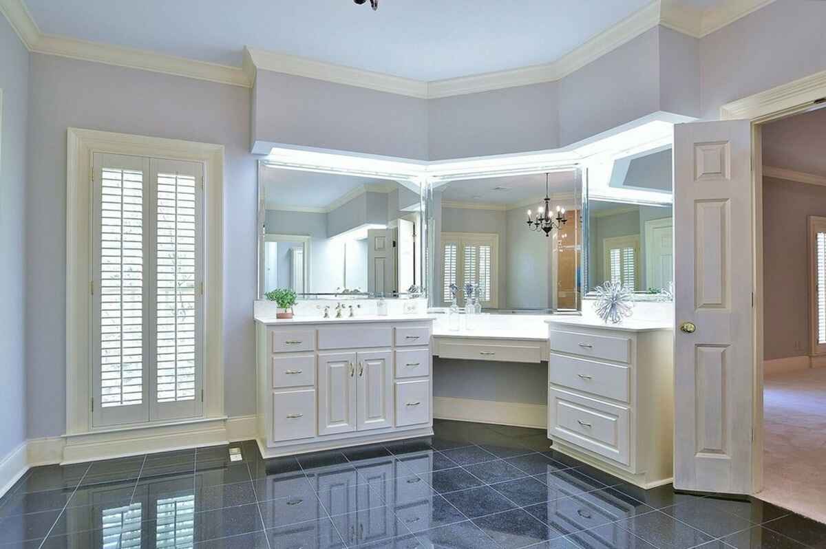 Vanity area in the bathroom displays custom cabinetry, a large mirror, and built-in lighting.