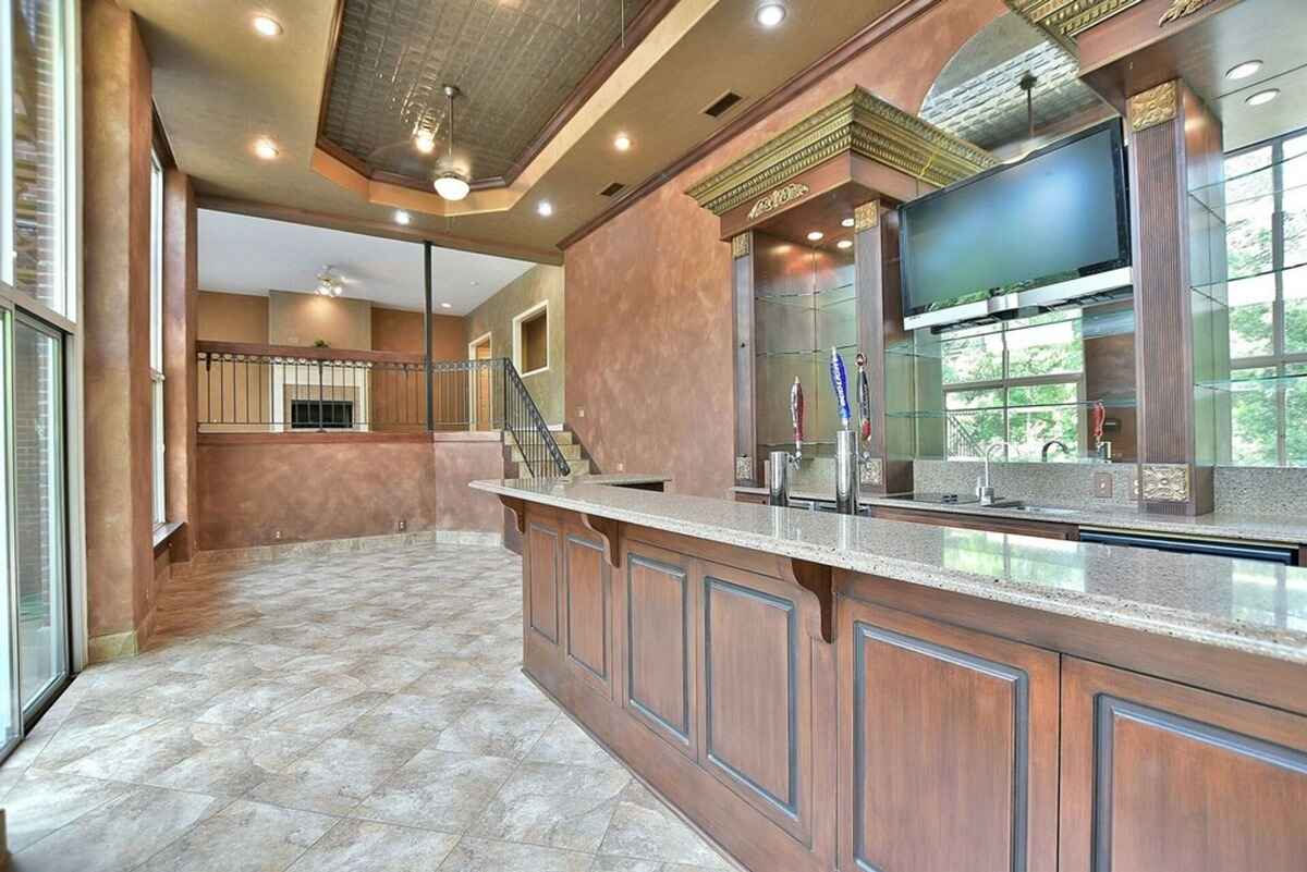 Luxurious bar area highlights custom cabinetry, a granite countertop, and detailed ceiling design.