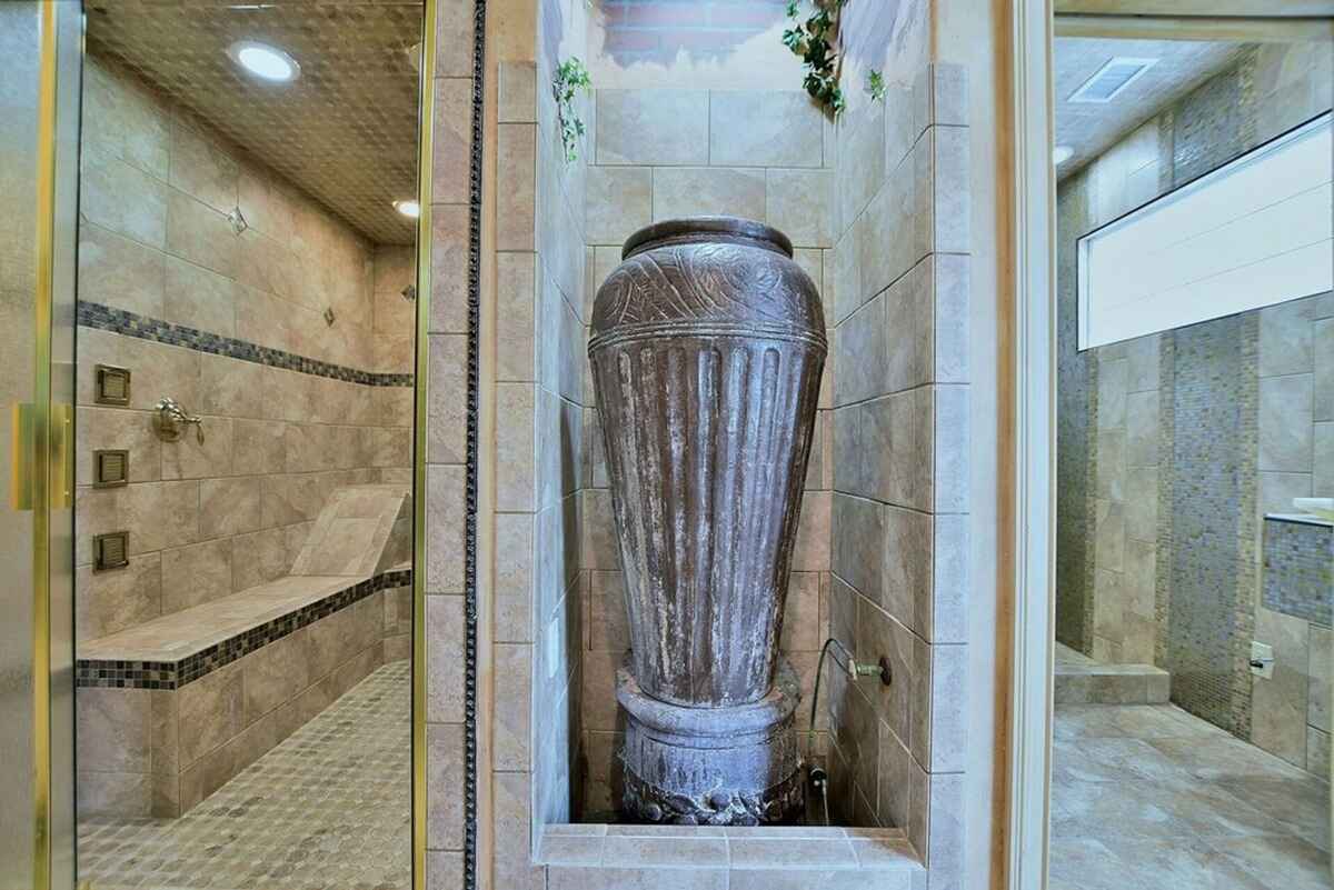 Large shower space features mosaic tiles, a built-in bench, and decorative elements.