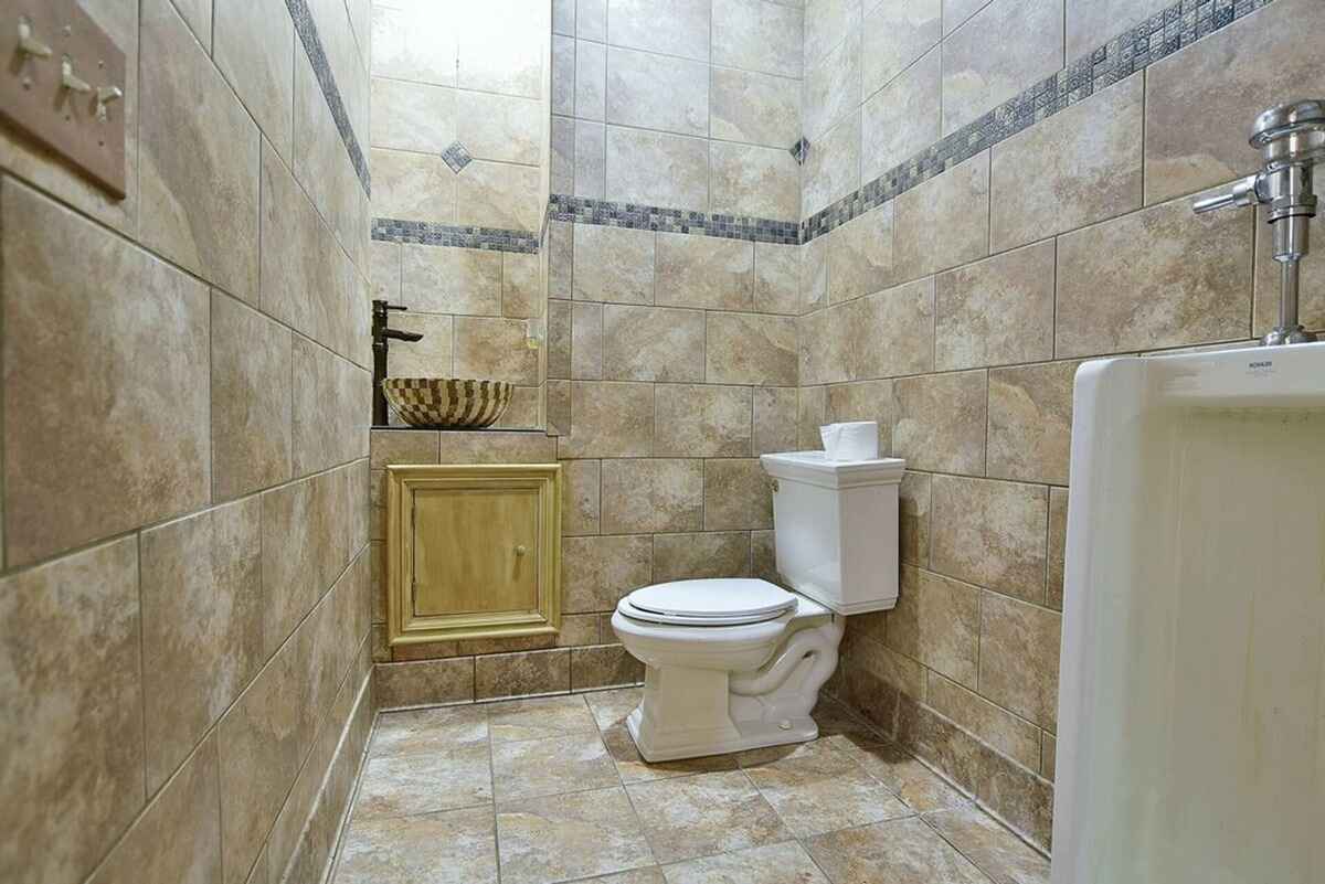 Modern tiled restroom includes a unique vessel sink and classic fixtures.