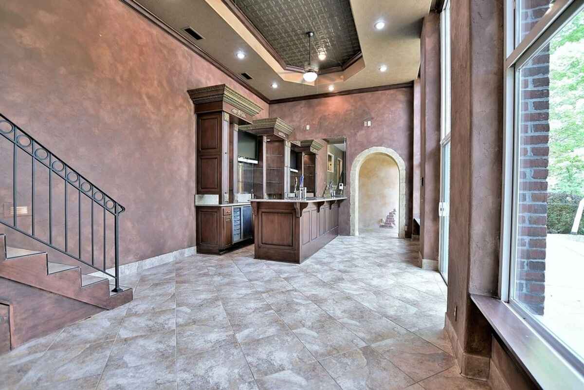 Bar and staircase area connects open spaces with rich wooden cabinetry and arched doorway.