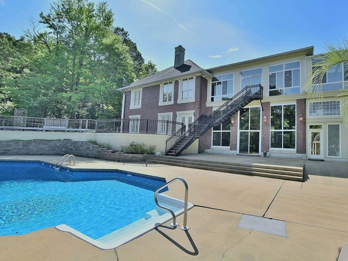 Rear view of the house highlights multiple levels, large windows, and direct access to the pool area.