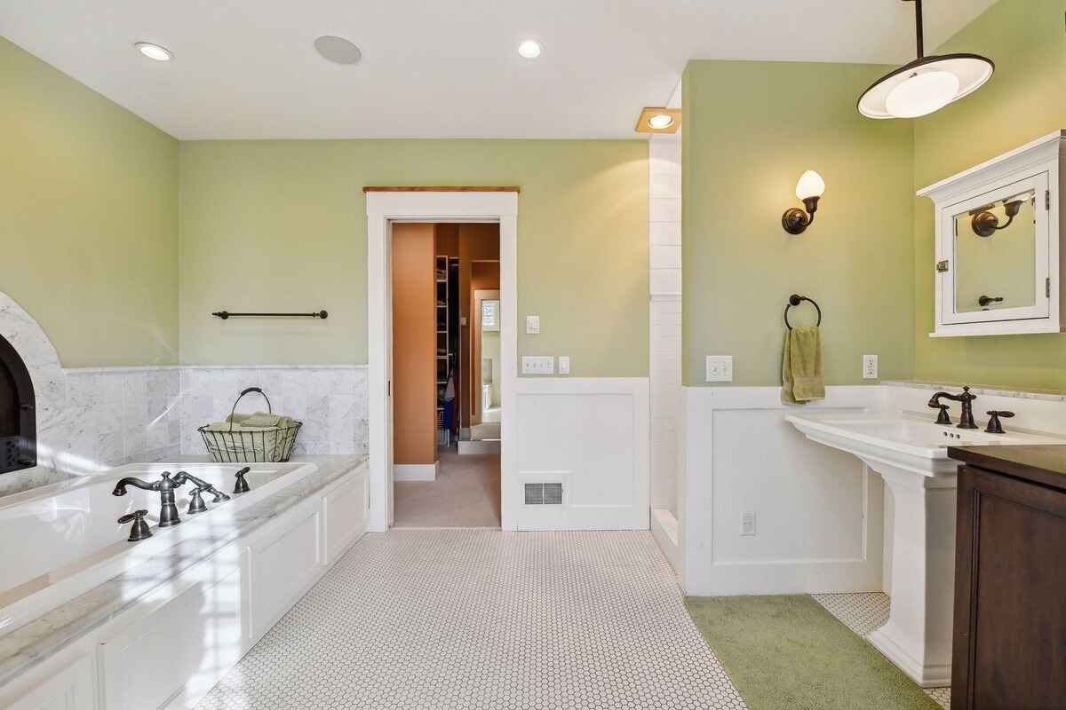 A bathroom includes a marble tub, dual vanities, and green-painted walls.