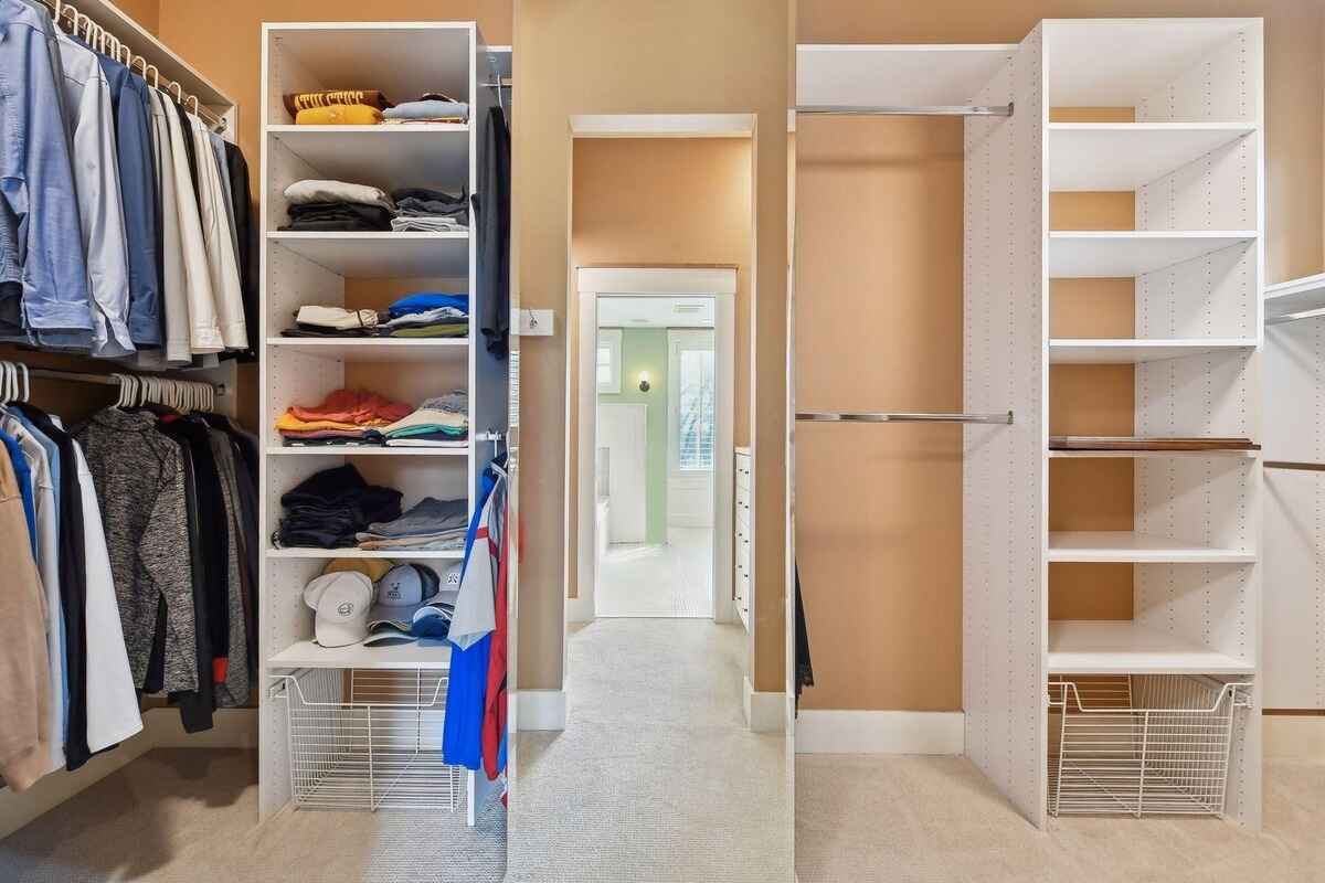 Walk-in closet features open shelving, hanging space, and a mirrored door.